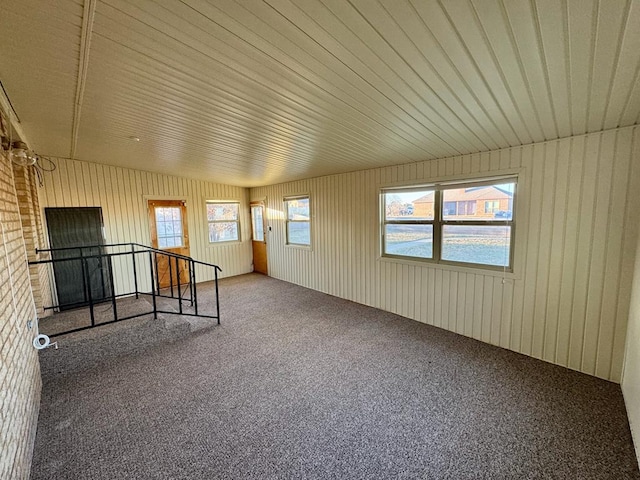 empty room with carpet flooring and wood walls