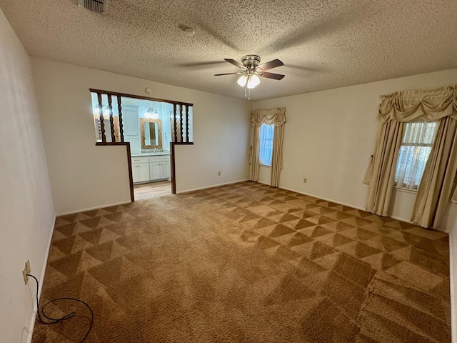 carpeted empty room with ceiling fan, plenty of natural light, and a textured ceiling