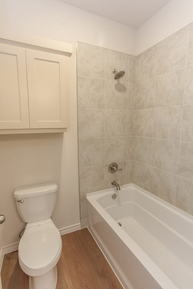 bathroom featuring tiled shower / bath combo, wood-type flooring, and toilet