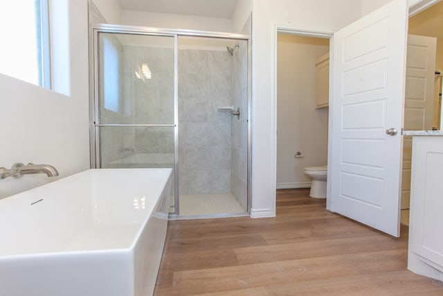 bathroom featuring hardwood / wood-style flooring, toilet, and separate shower and tub