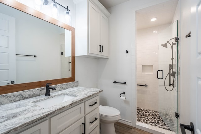 bathroom featuring vanity, hardwood / wood-style flooring, toilet, and a shower with door