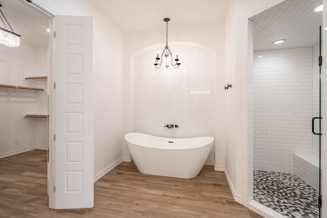 bathroom featuring hardwood / wood-style floors, separate shower and tub, and an inviting chandelier