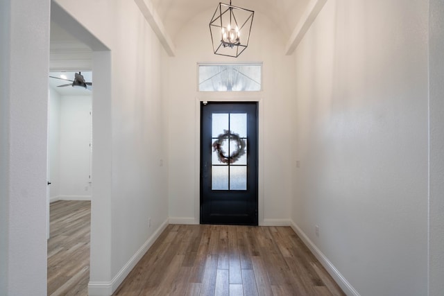 entrance foyer featuring hardwood / wood-style floors, ceiling fan with notable chandelier, and vaulted ceiling