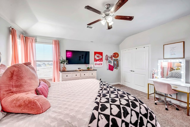 carpeted bedroom with ceiling fan, a closet, and vaulted ceiling