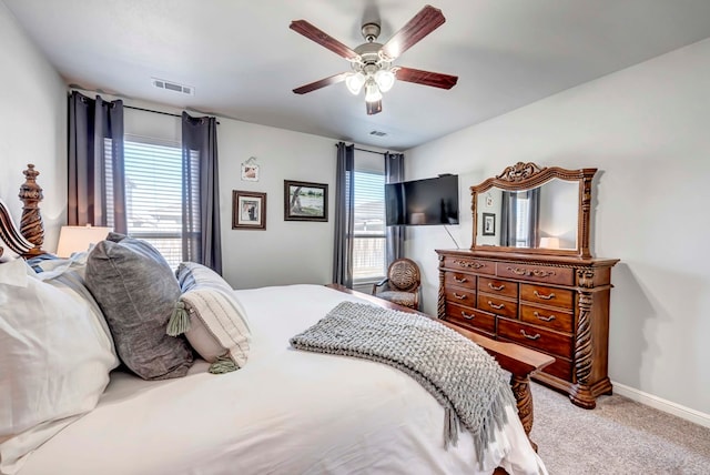 bedroom featuring ceiling fan, light carpet, and multiple windows