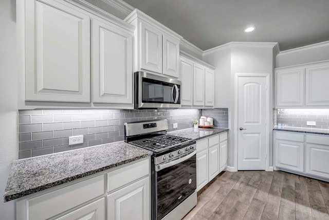 kitchen with white cabinets, light wood-type flooring, and appliances with stainless steel finishes