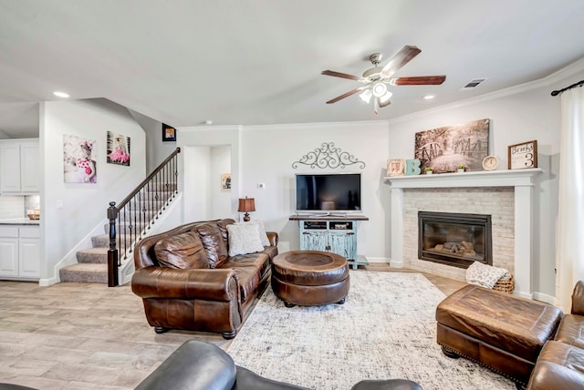 living room featuring ceiling fan, crown molding, light wood-type flooring, and a fireplace