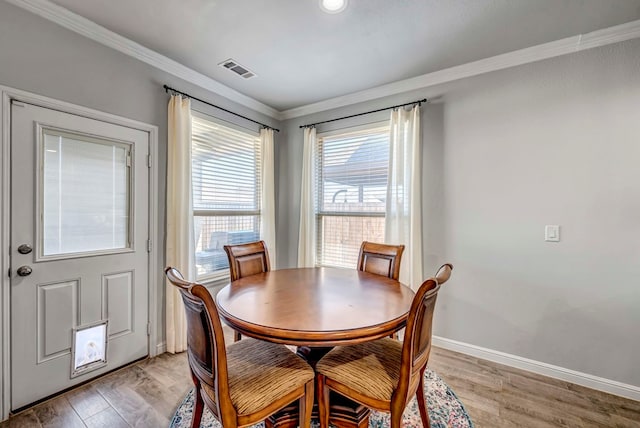 dining space with light hardwood / wood-style flooring and crown molding