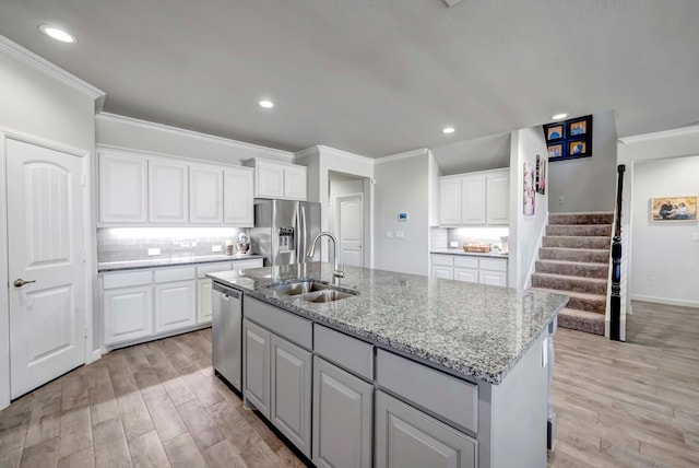 kitchen featuring a kitchen island with sink, sink, white cabinets, and stainless steel appliances