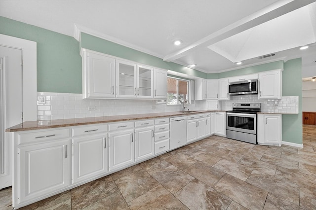 4715 N County Rd 1125, Midland, TX 79705 - kitchen featuring appliances with stainless steel finishes, backsplash, white cabinets, glass insert cabinets, and crown molding