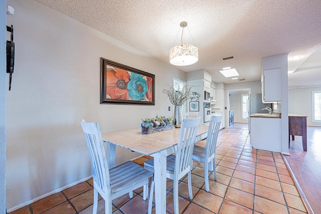 dining room with sink, light tile patterned floors, and a textured ceiling