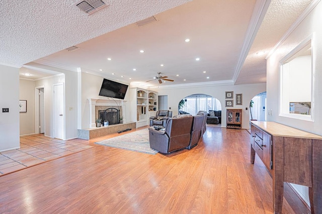 living room with light hardwood / wood-style floors, a tile fireplace, and a textured ceiling