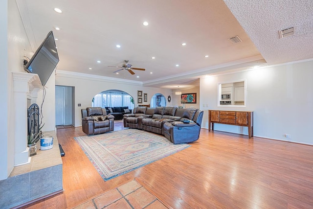 living room with a tray ceiling, crown molding, and light wood-type flooring