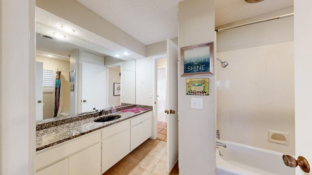 bathroom with tile patterned flooring, vanity, shower / washtub combination, and a textured ceiling