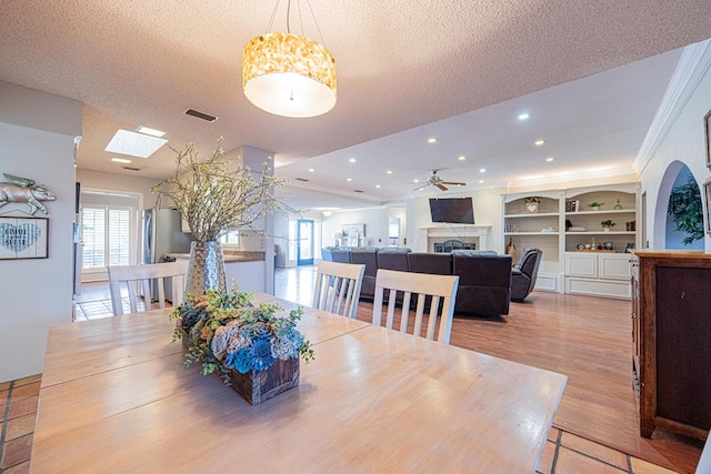 dining room featuring crown molding, ceiling fan, a textured ceiling, and light wood-type flooring