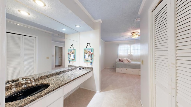 bathroom featuring ceiling fan, vanity, and a textured ceiling