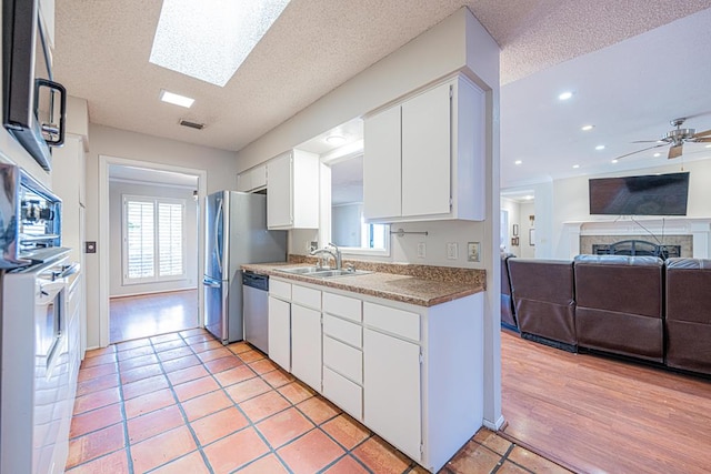 kitchen featuring appliances with stainless steel finishes, a wealth of natural light, sink, and white cabinets