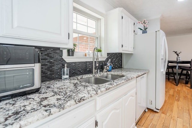1703 Laurel Ave, Odessa, TX 79761 - kitchen featuring decorative backsplash, white dishwasher, light wood finished floors, white cabinetry, and light stone countertops