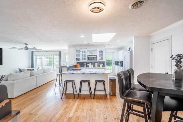 1703 Laurel Ave, Odessa, TX 79761 - dining space with a skylight, light wood-style flooring, a textured ceiling, recessed lighting, and a ceiling fan