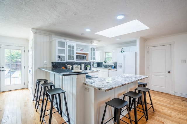1703 Laurel Ave, Odessa, TX 79761 - kitchen with white appliances, a skylight, a peninsula, a kitchen breakfast bar, and open shelves