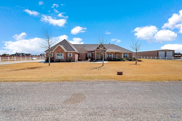 view of front of home featuring a front yard, brick siding, fence, and an outbuilding