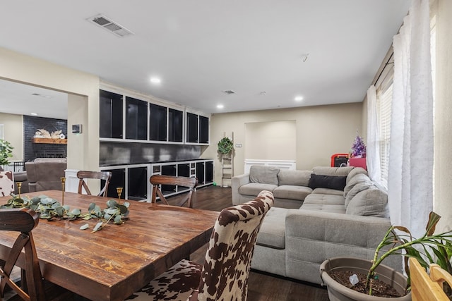 living room with dark wood-type flooring and a brick fireplace