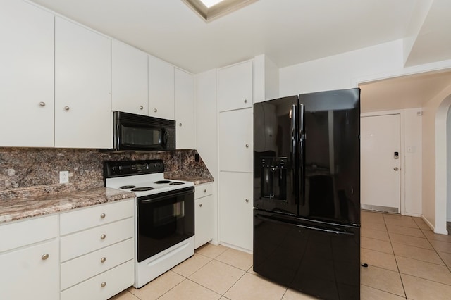 kitchen with light tile patterned floors, arched walkways, white cabinets, black appliances, and decorative backsplash