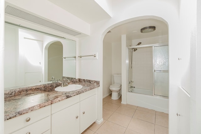bathroom with toilet, enclosed tub / shower combo, vanity, and tile patterned flooring