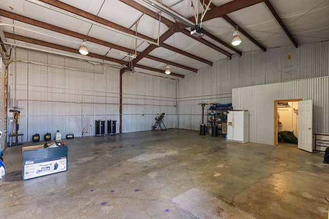 garage with a garage door opener and white refrigerator with ice dispenser