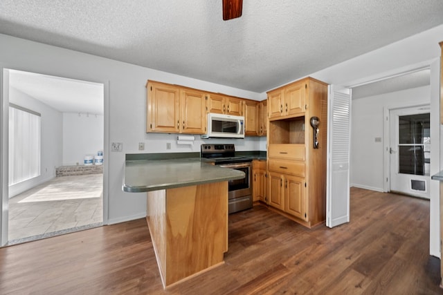 2100 Edgemere Rd, Big Spring, TX 79720 - kitchen with stainless steel range with electric cooktop, white microwave, a peninsula, dark wood finished floors, and dark countertops
