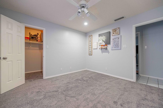 unfurnished bedroom with carpet flooring, a spacious closet, ceiling fan, a textured ceiling, and a closet