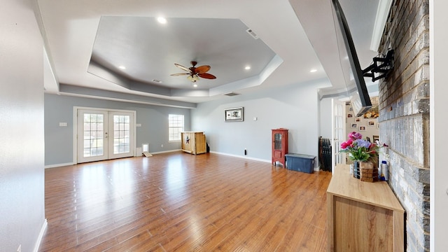 living room featuring a tray ceiling, ceiling fan, french doors, and wood-type flooring