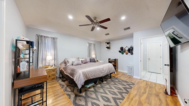 bedroom with a textured ceiling, light hardwood / wood-style flooring, and ceiling fan