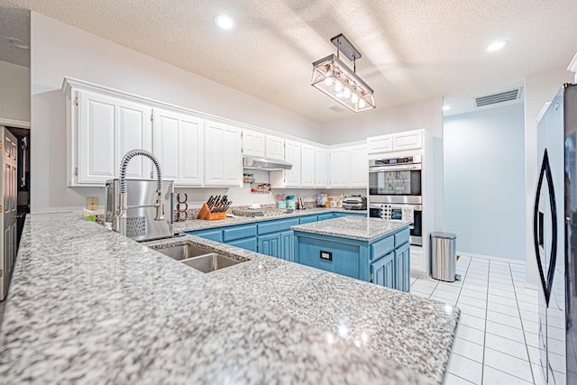 kitchen featuring stainless steel appliances, a kitchen island, blue cabinets, a textured ceiling, and white cabinets