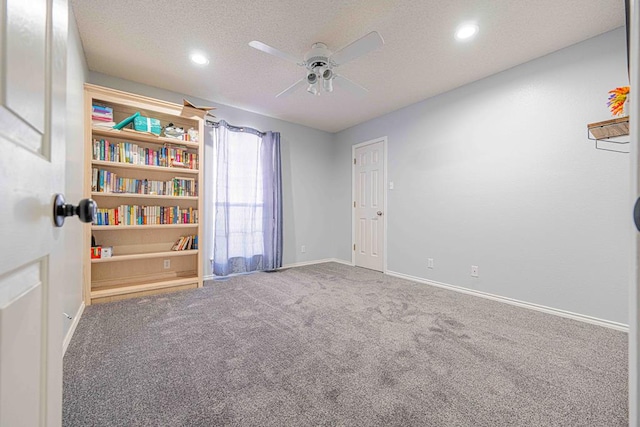 carpeted spare room featuring ceiling fan and a textured ceiling