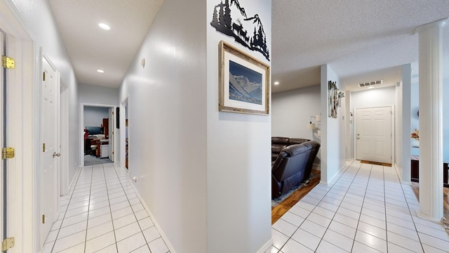 hall featuring light tile patterned floors and a textured ceiling