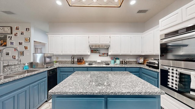 kitchen with light stone countertops, white cabinetry, a center island, stainless steel appliances, and blue cabinets