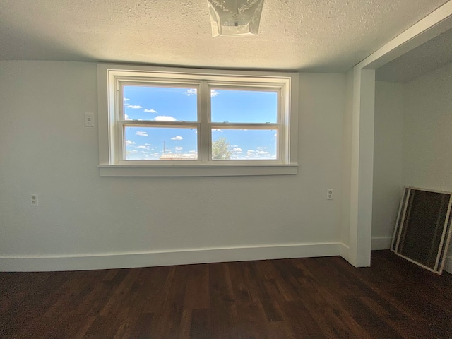 3007 S Anderson Rd, Big Spring, TX 79720 - spare room featuring dark wood finished floors, plenty of natural light, and a textured ceiling