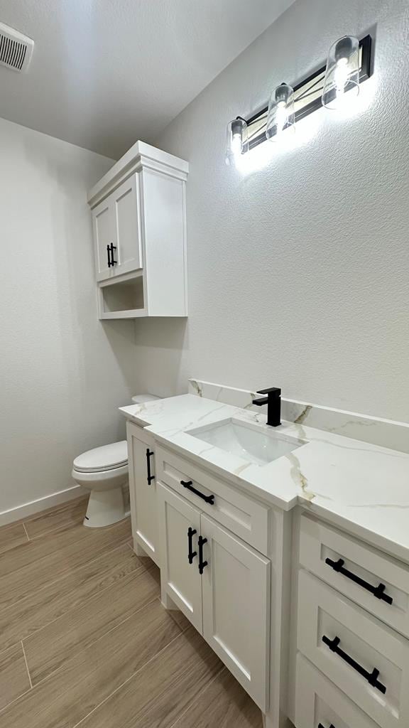 2118 S County Rd 1059, Midland, TX 79706 - half bath featuring vanity, toilet, wood finished floors, and baseboards
