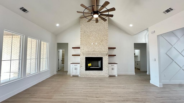 2118 S County Rd 1059, Midland, TX 79706 - unfurnished living room with a ceiling fan, high vaulted ceiling, a brick fireplace, baseboards, and light wood-style flooring
