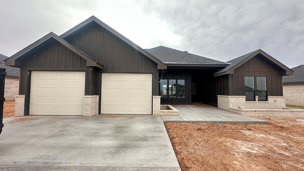 view of front of house with concrete driveway, an attached garage, brick siding, and board and batten siding