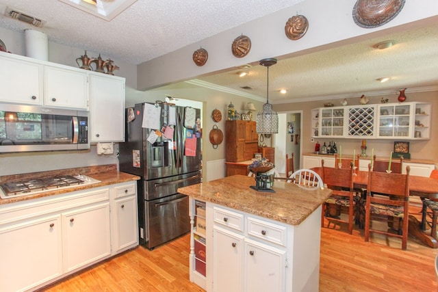 702 Capri Ct, Big Spring, TX 79720 - kitchen featuring stainless steel appliances, crown molding, a textured ceiling, light wood-style floors, and white cabinets
