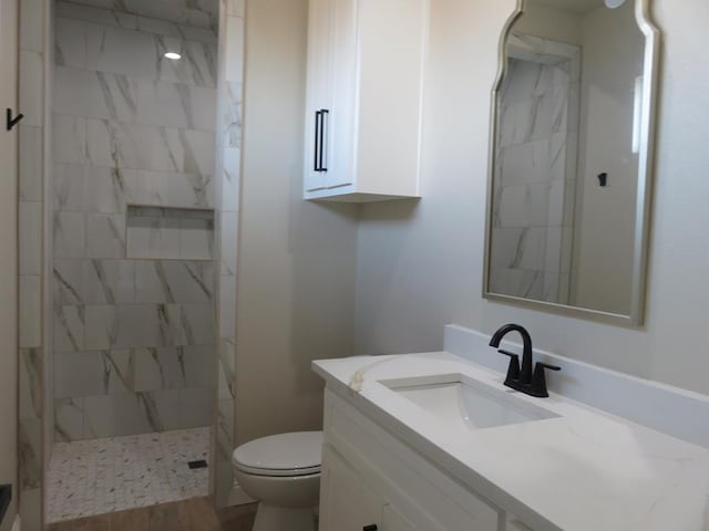 bathroom featuring vanity, toilet, and a tile shower
