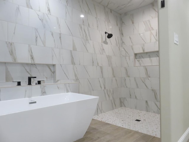 bathroom featuring a soaking tub, wood finished floors, and a tile shower