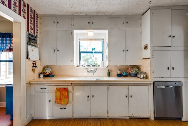 707 E County Rd 132, Midland, TX 79706 - kitchen with stainless steel dishwasher, tasteful backsplash, a sink, white cabinetry, and a textured ceiling