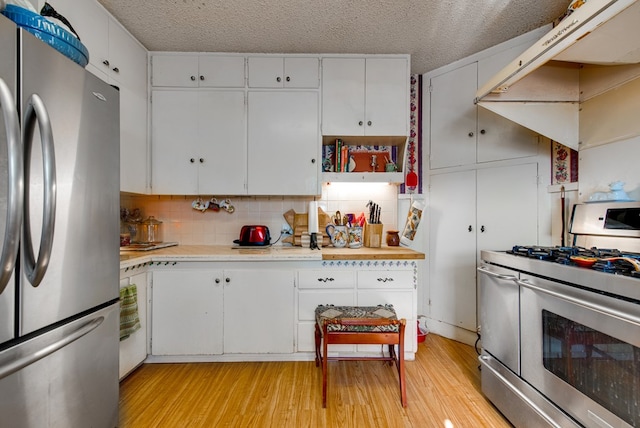 707 E County Rd 132, Midland, TX 79706 - kitchen featuring stainless steel appliances, light wood-style floors, light countertops, a textured ceiling, and white cabinetry