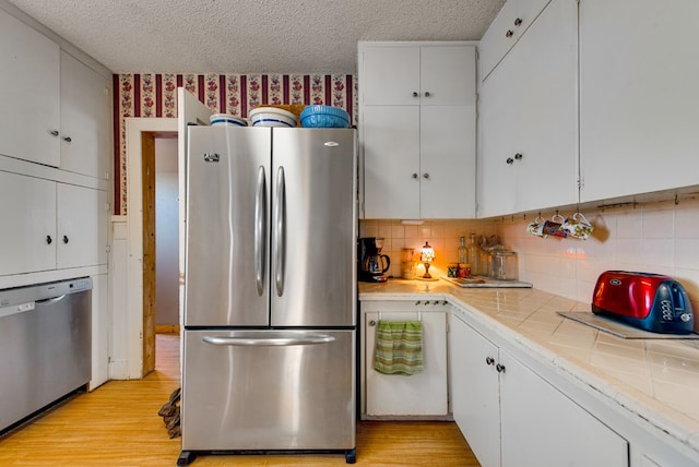 707 E County Rd 132, Midland, TX 79706 - kitchen with stainless steel appliances, tile countertops, a textured ceiling, white cabinetry, and decorative backsplash