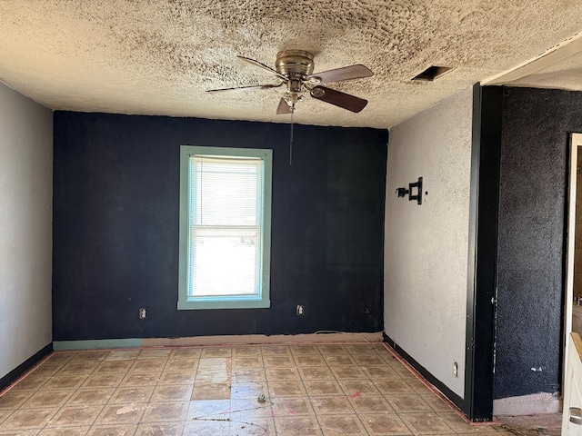 spare room with visible vents, a textured ceiling, a ceiling fan, and baseboards