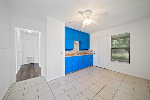 1410 Tucson Rd, Big Spring, TX 79720 - kitchen featuring blue cabinets, light tile patterned flooring, a ceiling fan, light countertops, and backsplash