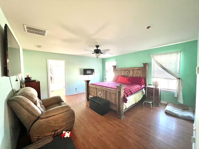 bedroom with multiple windows, ceiling fan, ensuite bathroom, and dark hardwood / wood-style floors